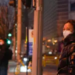Una mujer con una mascarilla en una calle de Pekín