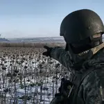 Un soldado ucraniano señala el humo que se levanta en su posición en la línea del frente cerca de Soledar