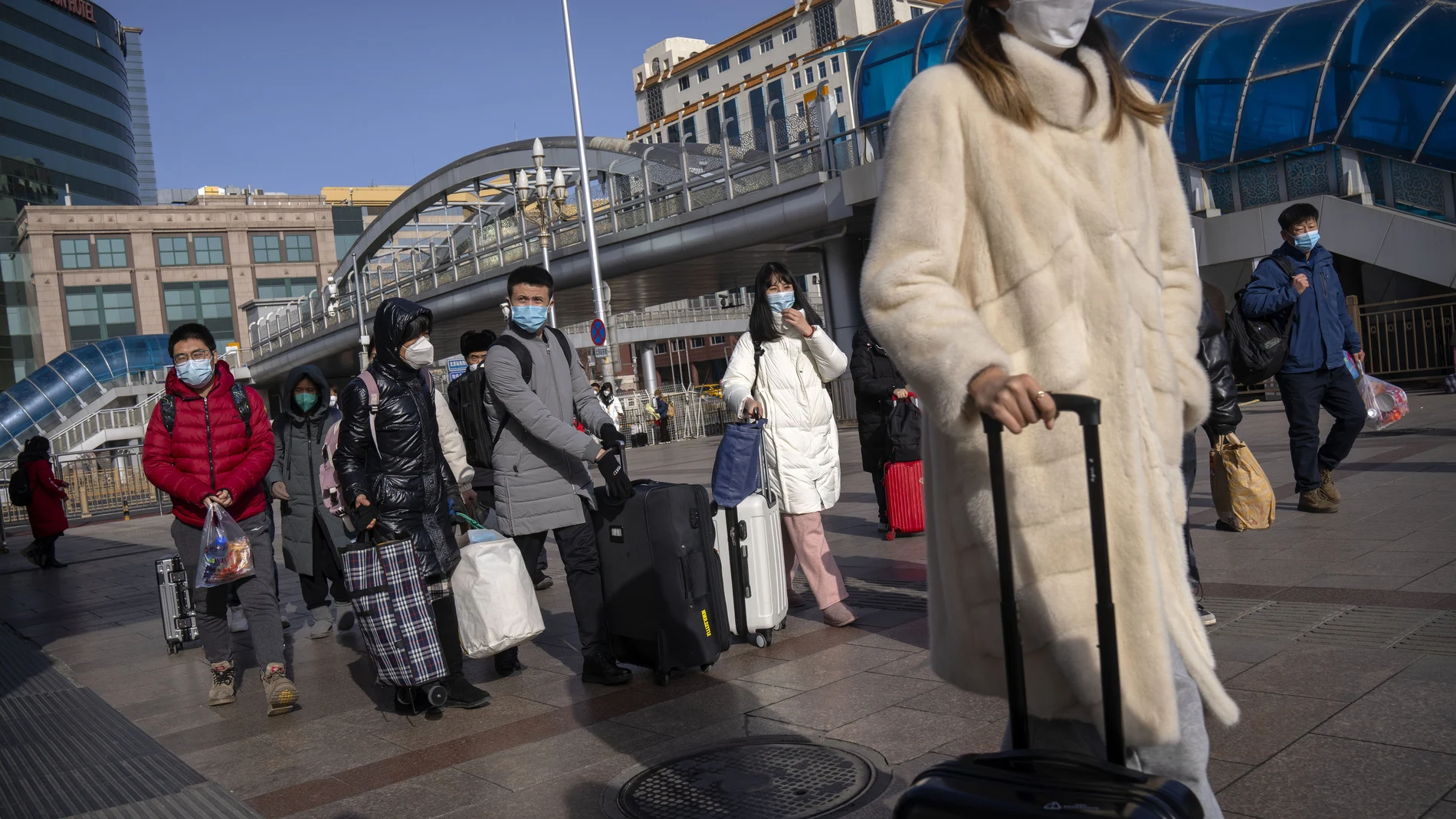 Viajeros usando mascarilla en la entrada de la estación de tren de Beijing.