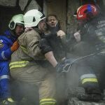 Bomberos del Servicio Estatal de Emergencias de Ucrania sacan a una mujer herida de entre los escombros de un edificio tras un ataque ruso con cohetes el sábado en Dnipro