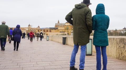 Transeúntes y turistas por el famoso puente de San Rafael con vistas a la Mezquita de Córdoba, en una fría tarde