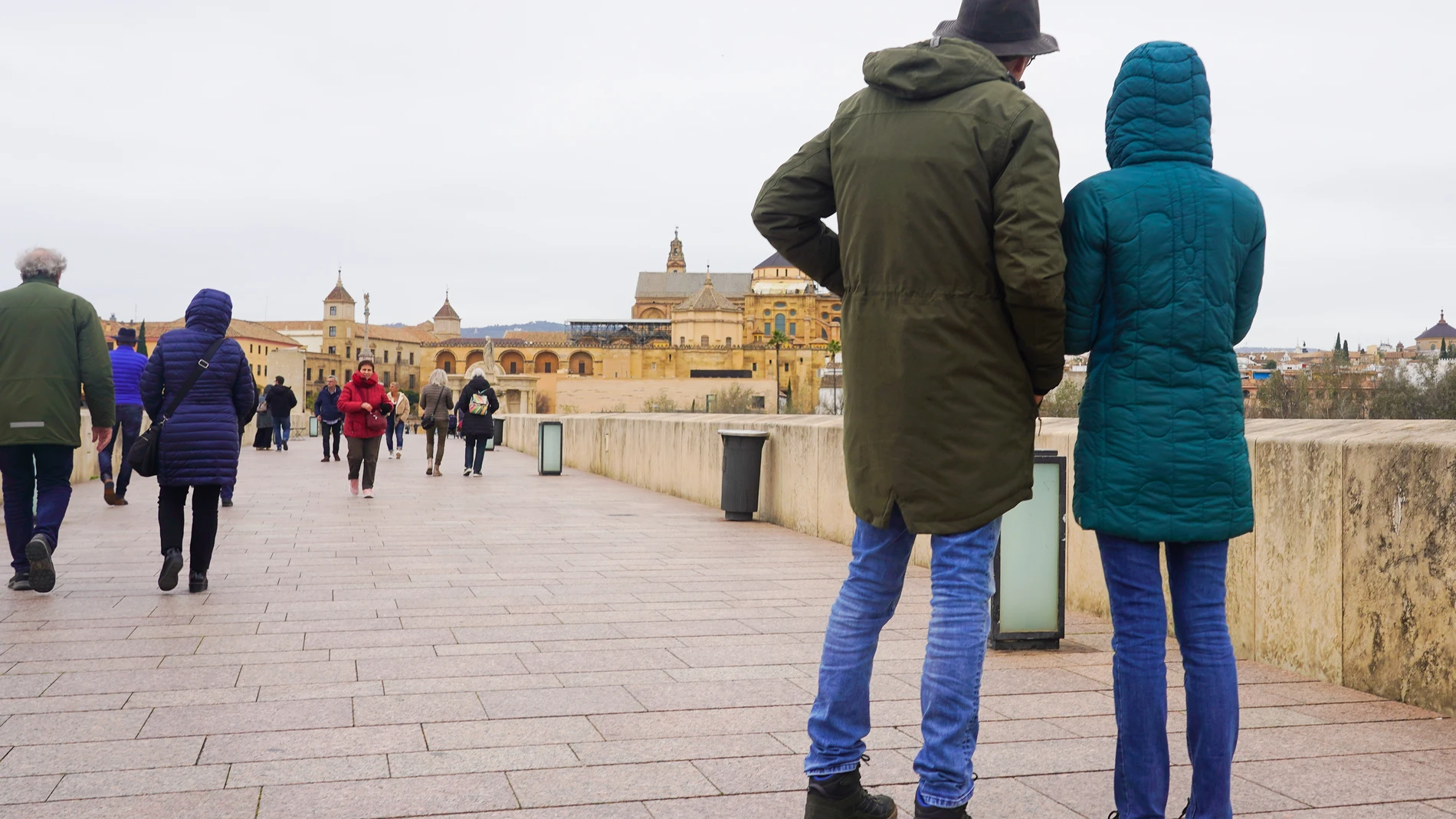 Transeúntes y turistas por el famoso puente de San Rafael con vistas a la Mezquita de Córdoba, en una fría tarde