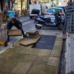 Trabajadores retiran una terraza situada en una de las bandas de estacionamiento regulado en una vía aledaña a la calle Ponzano de Madrid