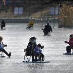 Una madre juega con su hijo en un estanque helado en un parque de Beijing (China)