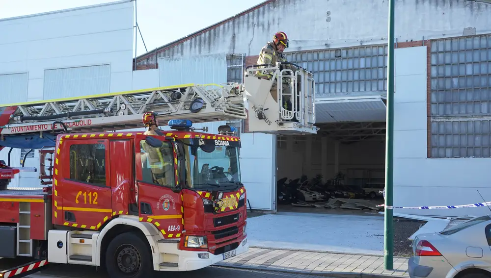 Una escala de los bomberos interviene para retirar unas chapas desprendidas en una nave de la calle Ducado en Valladolid