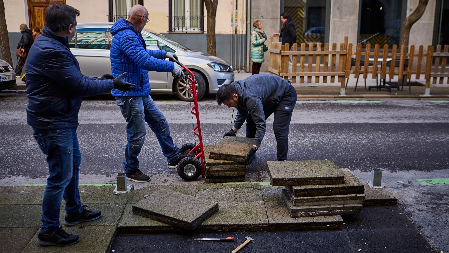 Trabajadores retiran una terraza situada en una de las bandas de estacionamiento regulado en una vía aledaña a la calle Ponzano de Madrid