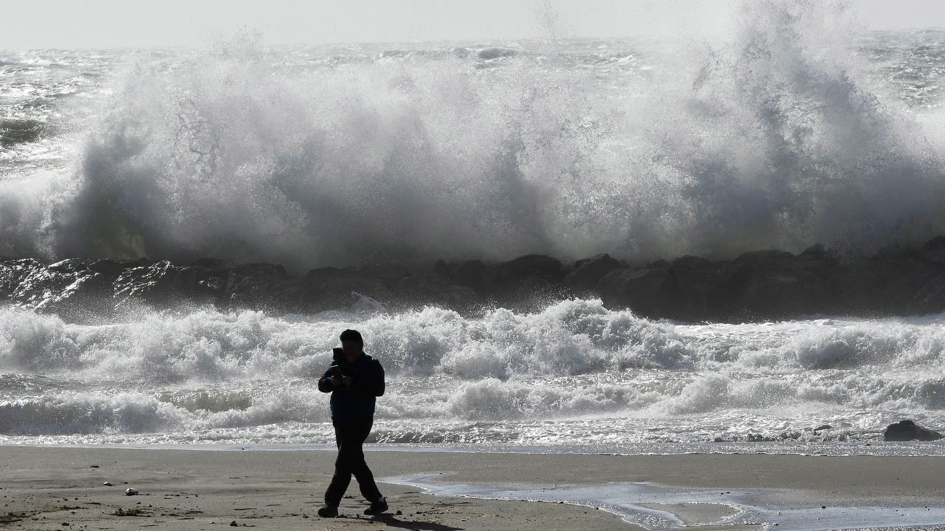 Una persona pasea por la playa de El Zapillo, en Almería durante el temporal de viento que azota la provincia y por la que la AEMET ha declarado la alerta naranja por rachas de hasta 80 km/h