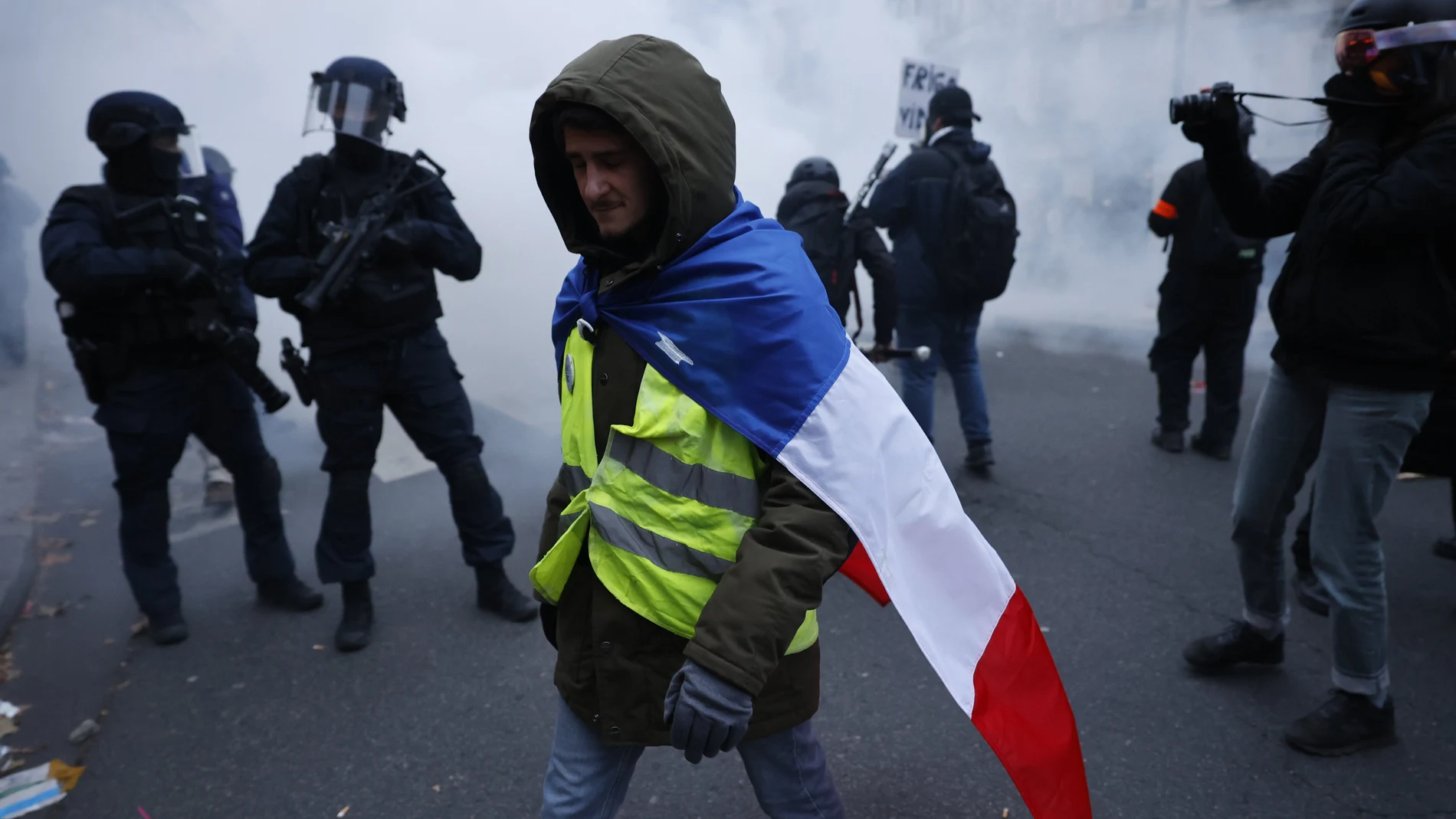 Un manifestante pasa junto a varios agentes de policía en París