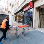 Un trabajador de la funeraria con una camilla en la puerta del portal del domicilio donde han sido asesinadas una madre y su hija de ocho años presuntamente por el novio de la madre
