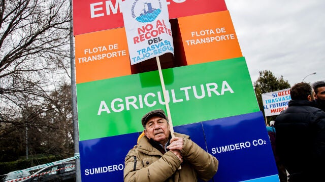 Un hombre sostiene una pancarta durante una concentración para evitar que recorten el trasvase Tajo-Segura, en las inmediaciones del Palacio de la Moncloa esta mañana