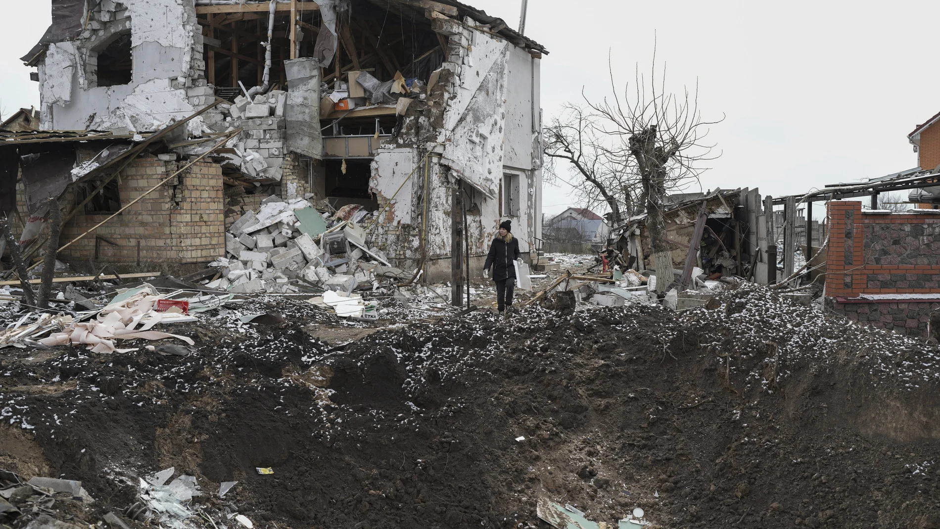Una mujer sobre un cráter junto a una casa destruida tras un ataque ruso con misiles en Hlevakha, en la región de Kyiv