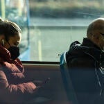 Dos personas con mascarillas viajan en un transporte público