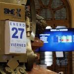 Un calendario del día de hoy, 27 de enero, delante de un panel del Ibex 35