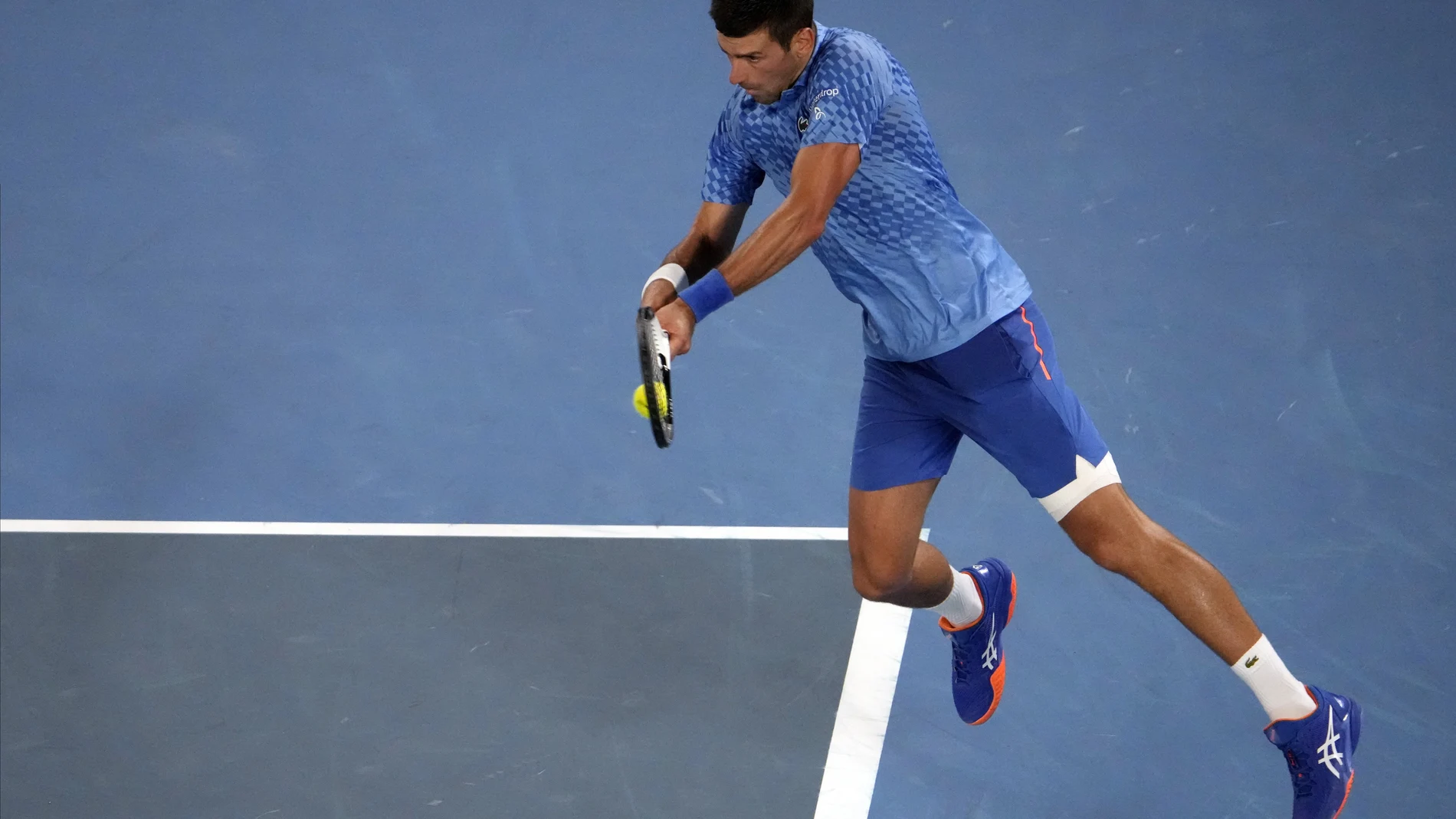 Novak Djokovic golpea un revés a dos manos desde el fondo de la pista