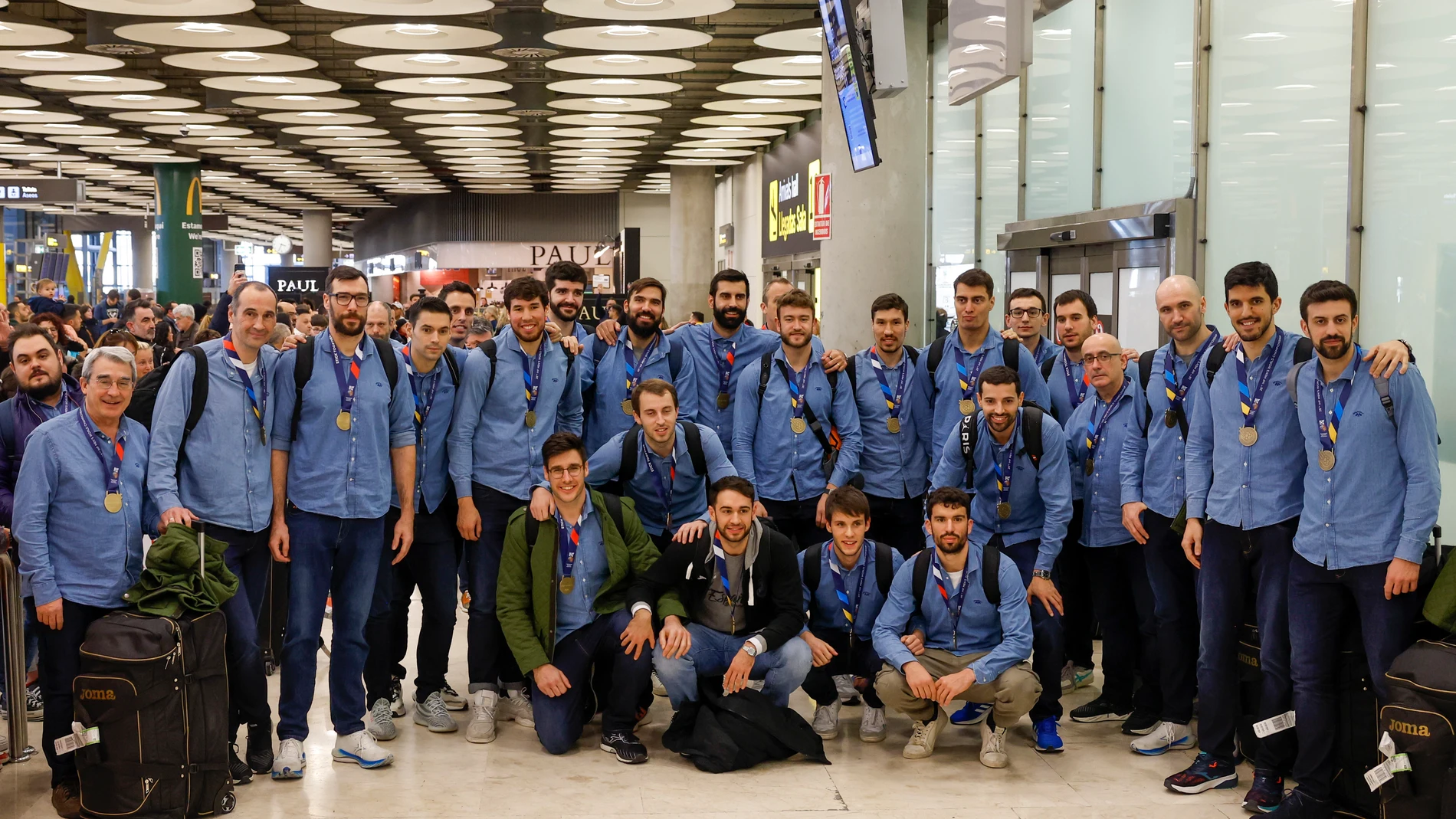 La selección española de balonmano, tanto jugadores como cuerpo técnico, posan en Barajas con el bronce que ganaron en el Mundial