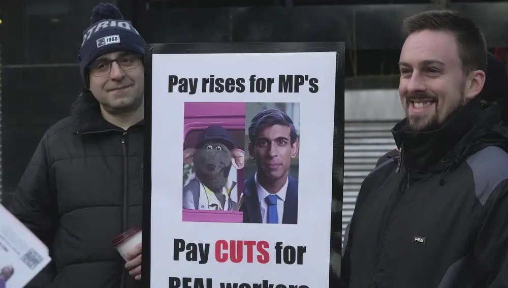 Trabajadores ferroviarios sostienen un cartel con imágenes de un personaje de televisión Roland Rat, izquierda, y el primer ministro británico Rishi Sunak durante una huelga fuera de la estación de Euston en Londres