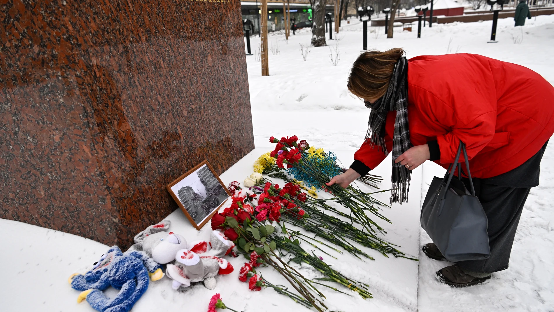 Una mujer deposita flores en memoria de los fallecidos en el ataque del fin de semana contra un bloque de viviendas en Dnipro, ante el monumento a la famosa poetisa ucraniana Lesya Ukrainka, en Moscú