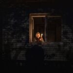 Catherine, 70, holds a candle in the window of her home during a power outage in Borodyanka, Kyiv region, Ukraine