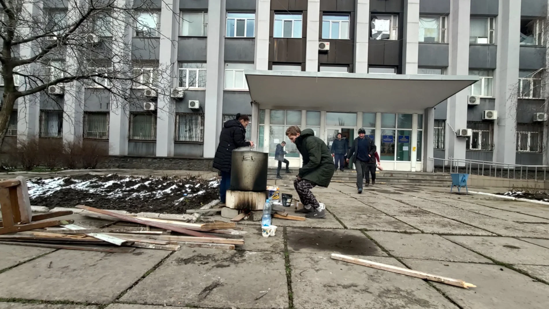 Dos personas se calientan en un fuego en la calle en Mariupol