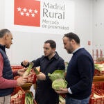 El agricultor Félix Ledesma charla con el director de IMIDRA, Sergio López, y con el presidente de UCAM, Mariano García-Patrón, al llevar el pasado miércoles coliflor, col kale y calçots a la nave de Madrid Rural en Fuenlabrada.