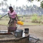 Una mujer de Mozambique llena cubos de agua 