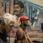 AME565. CARACAS (VENEZUELA), 08/03/2023.- Varias personas caminan frente a un graffiti con la imagen del presidente de Venezuela, Nicolás Maduro, el 3 de marzo de 2023, en Caracas (Venezuela). El 8 de marzo de 2013 Nicolás Maduro juró asumir la Presidencia de Venezuela con "mano dura", una promesa que hoy, cuando cumple diez años en el cargo, sigue viva y se ha cumplido a rajatabla, especialmente cuando la crispación política y los múltiples enemigos de la revolución bolivariana amenazaron su continuidad en el poder. EFE/ Miguel Gutierrez