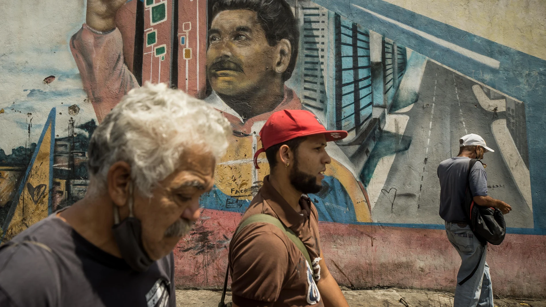 AME565. CARACAS (VENEZUELA), 08/03/2023.- Varias personas caminan frente a un graffiti con la imagen del presidente de Venezuela, Nicolás Maduro, el 3 de marzo de 2023, en Caracas (Venezuela). El 8 de marzo de 2013 Nicolás Maduro juró asumir la Presidencia de Venezuela con "mano dura", una promesa que hoy, cuando cumple diez años en el cargo, sigue viva y se ha cumplido a rajatabla, especialmente cuando la crispación política y los múltiples enemigos de la revolución bolivariana amenazaron su continuidad en el poder. EFE/ Miguel Gutierrez