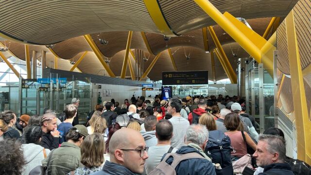 Centenares de viajeros hacen cola ayer domingo en un control de seguridad en la T-4 de Barajas