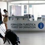 Varias personas pasan por delante de la Oficina de Turismo del Aeropuerto Internacional de la Región de Murcia