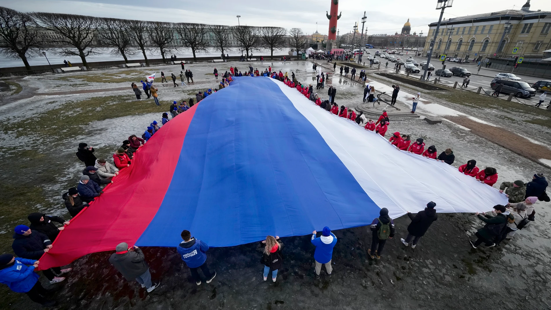Young people unfurl a giant Russian flag during an action to mark the ninth anniversary of the Crimea annexation from Ukraine in St. Petersburg, Russia, Saturday, March 18, 2023. (AP Photo/Dmitri Lovetsky)