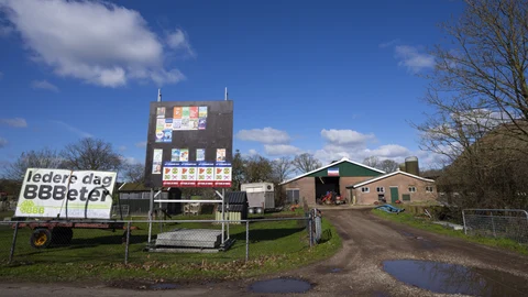 An upside-down Dutch flag was hung on a barn in protest against the Dutch government's plans to drastically reduce emissions of nitrogen pollutants by the country's agricultural sector, as posters of political parties for the provincial elections, with one of the Farmer Citizen Movement BBB, left, are seen at a farm in Okkenbroek, eastern Netherlands, Wednesday, March 15, 2023. Local elections with national consequences opened Wednesday in the Netherlands as voters cast their ballots for the country's 12 provincial legislatures, which in turn elect the national parliament's upper house.
