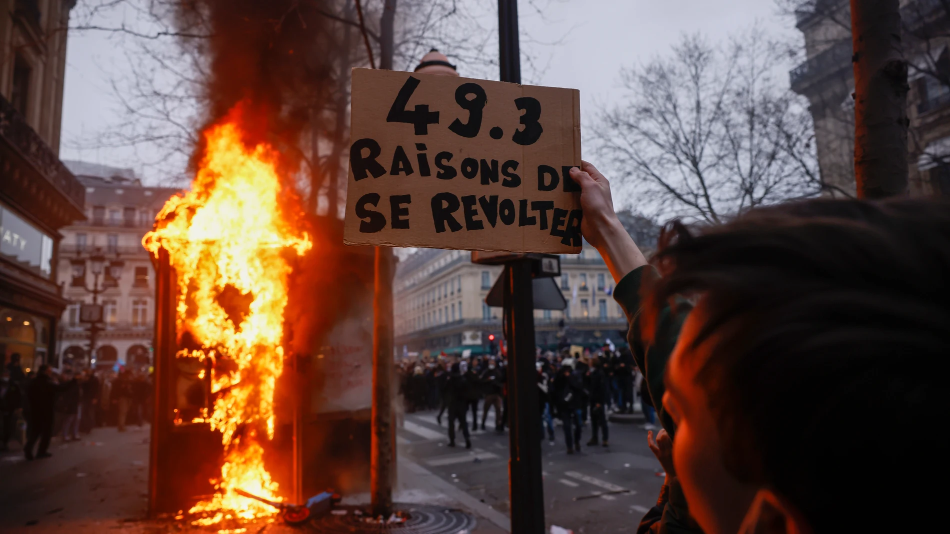 A protester holds a placard that reads, "49.3, reason to rebel", march at the end of a rally in Paris, Thursday, march 23, 2023. French unions are holding their first mass demonstrations Thursday since President Emmanuel Macron enflamed public anger by forcing a higher retirement age through parliament without a vote. (AP Photo/Thomas Padilla)