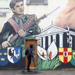 Un joven pasa con un patín junto a un mural republicano en Belfast