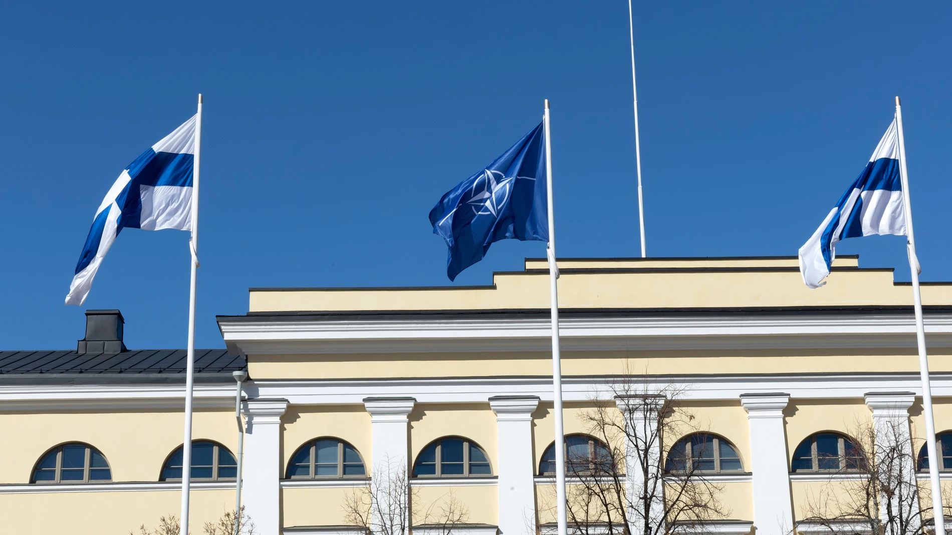 -FOTODELDÍA- HELSINKI (FINLANDIA), 04/04/2023.- Dos banderas finlandesas ondean junto a la bandera de la OTAN frente a la sede del Ministerio de Asuntos Exteriores de Finlandia, este martes en Helsinki. El ingreso de Finlandia en la OTAN, consumado hoy en tiempo récord, pone fin a casi ocho décadas de una neutralidad militar -inicialmente impuesta por Moscú y luego voluntaria- que casi con seguridad hubiera continuado de no producirse la invasión rusa de Ucrania. EFE/ Mauri Ratilainen