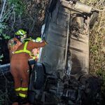 Los bomberos tratan de liberar al hombre cuyo coche cayó al barranco