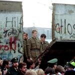 East German border guards look through a hole in the Berlin Wall after demonstrators pulled down the segment at Brandenburg Gate in Berlin, in this Nov. 11, 1989.
