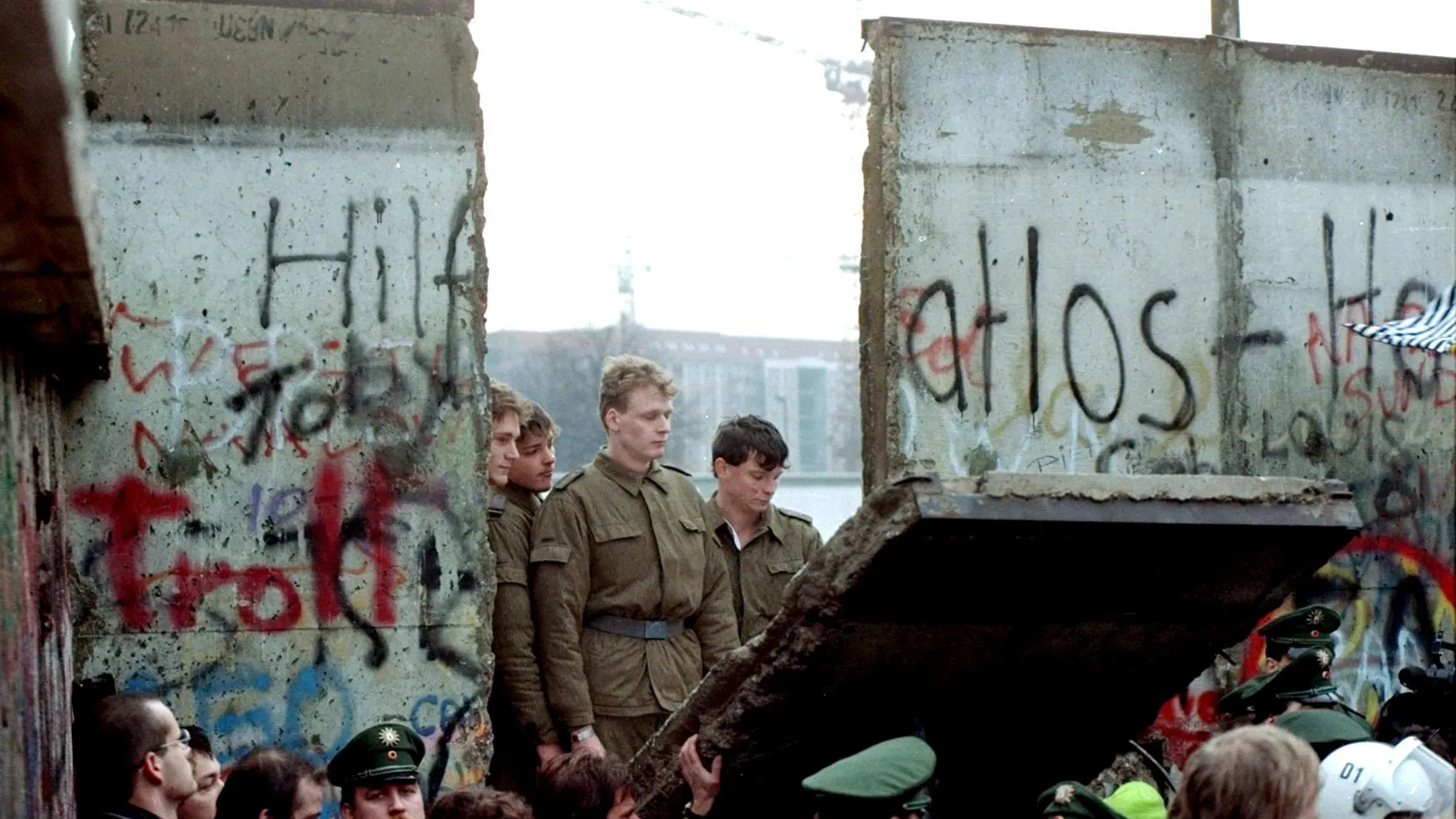 East German border guards look through a hole in the Berlin Wall after demonstrators pulled down the segment at Brandenburg Gate in Berlin, in this Nov. 11, 1989.