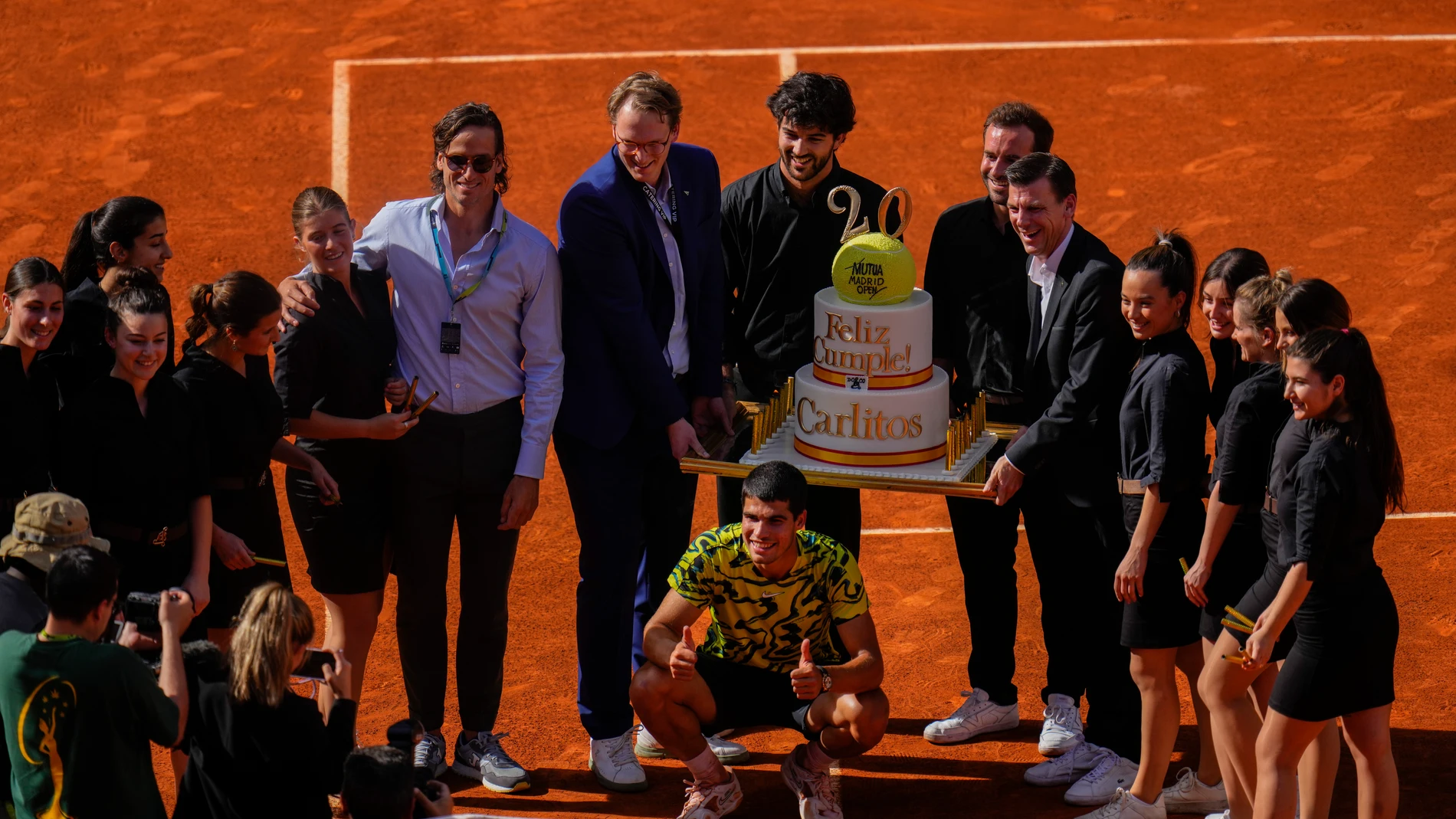 Carlos Alcaraz, of Spain, center down, poses with a cake for his 20th birthday after his victory over Borna Coric, of Croatia, during men's semifinal at the Madrid Open tennis tournament in Madrid, Spain, Friday, May 5, 2023. (AP Photo/Manu Fernandez)