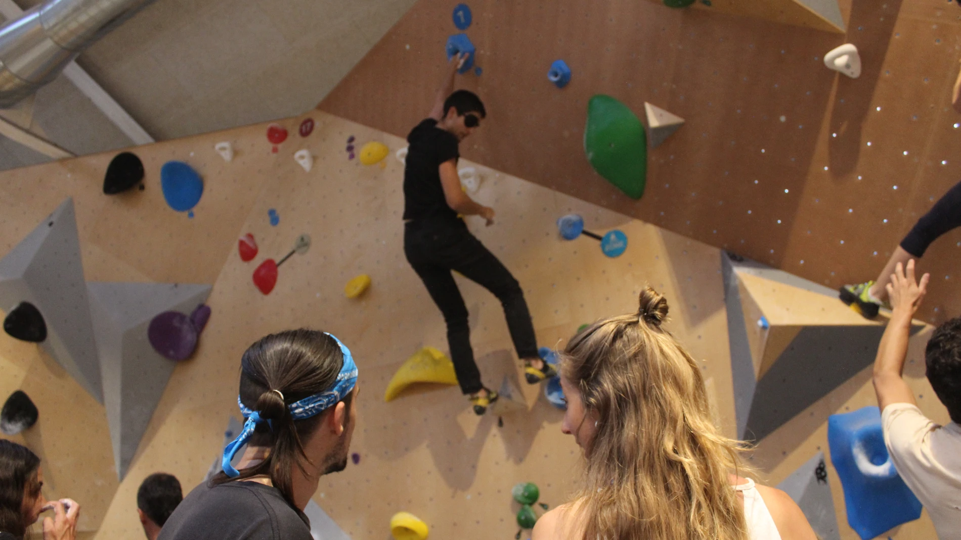 Pati, escaladora de 28 años, y su amigo Miguel, 29 años, ayudan a completar una vía a otro aficionado a la escalada en el rocódromo Arkose en Tetuán