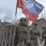 A still image taken from a handout video made available by Denis Pushilin, head of the self-proclaimed Donetsk People&#39;s Republic (DPR) telegram channel shows Denis Pushilin (L) installing a DPR flag atop of a damaged building in Bakhmut, eastern Ukraine, 23 May 2023