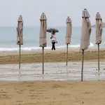 Una persona pasea bajo la lluvia por la playa de El Postiguet de Alicante 