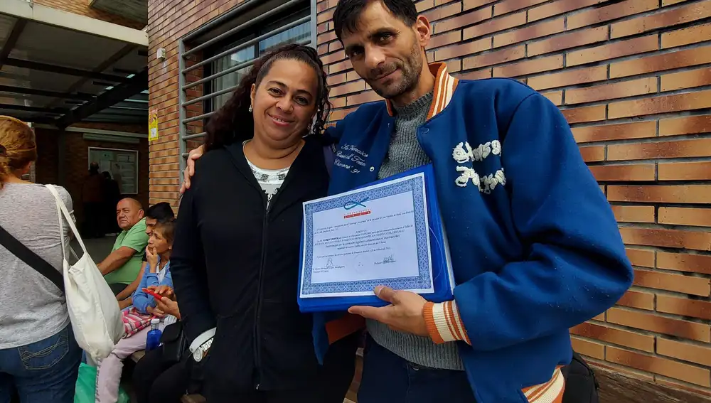 Ana, hondureño de 53 años, y Florín, rumano de 40 años, muestran el diploma del tercer taller de geriatría de Florín el pasado martes 23 de mayo en Batán, un barrio del sur de Madrid.
