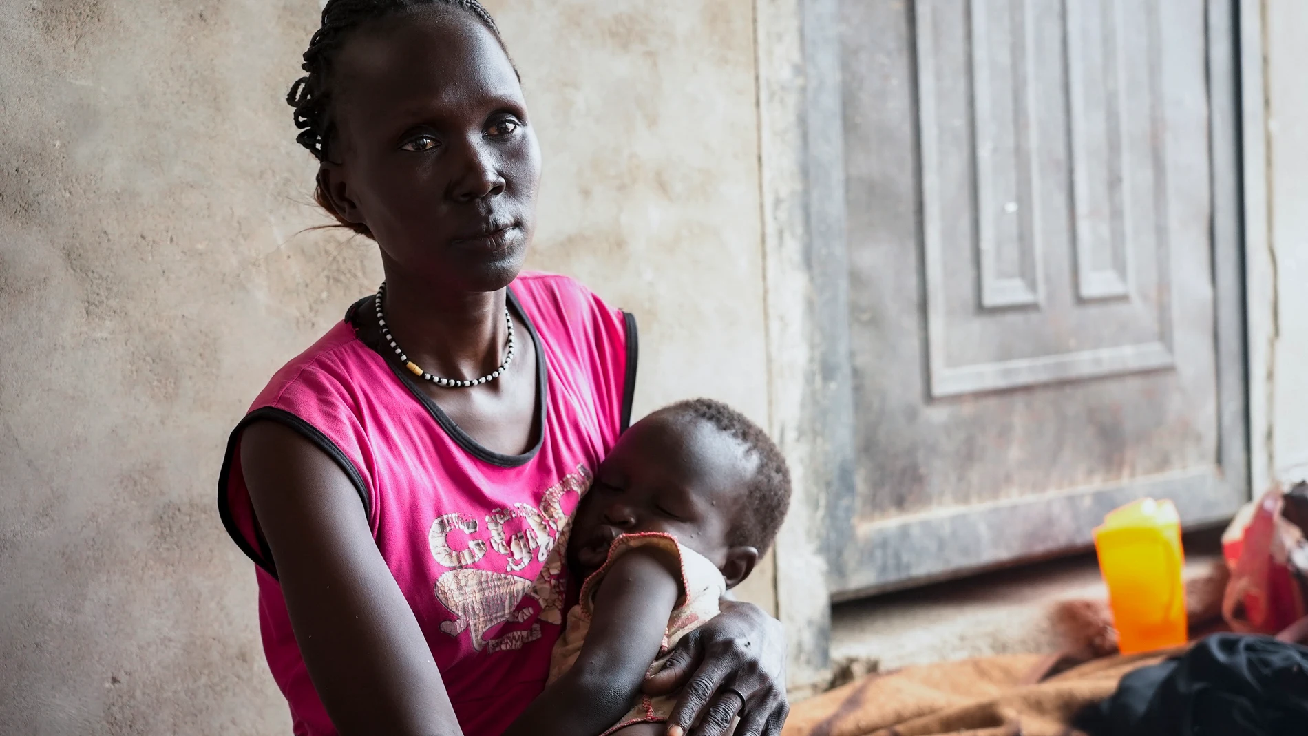 South Sudanese Alwel Ngok, 31, who fled from Sudan, sits holding her son in a church in Renk, South Sudan Tuesday, May 16, 2023. Tens of thousands of South Sudanese are flocking home from neighboring Sudan, which erupted in violence last month. (AP Photo/Sam Mednick)