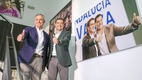 Juanma Moreno y José Luis Sanz, junto a un retrato del presidente andaluz con Feijóo