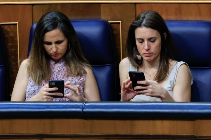 Irene Montero y Ione Belarra miran sus móviles en el Congreso