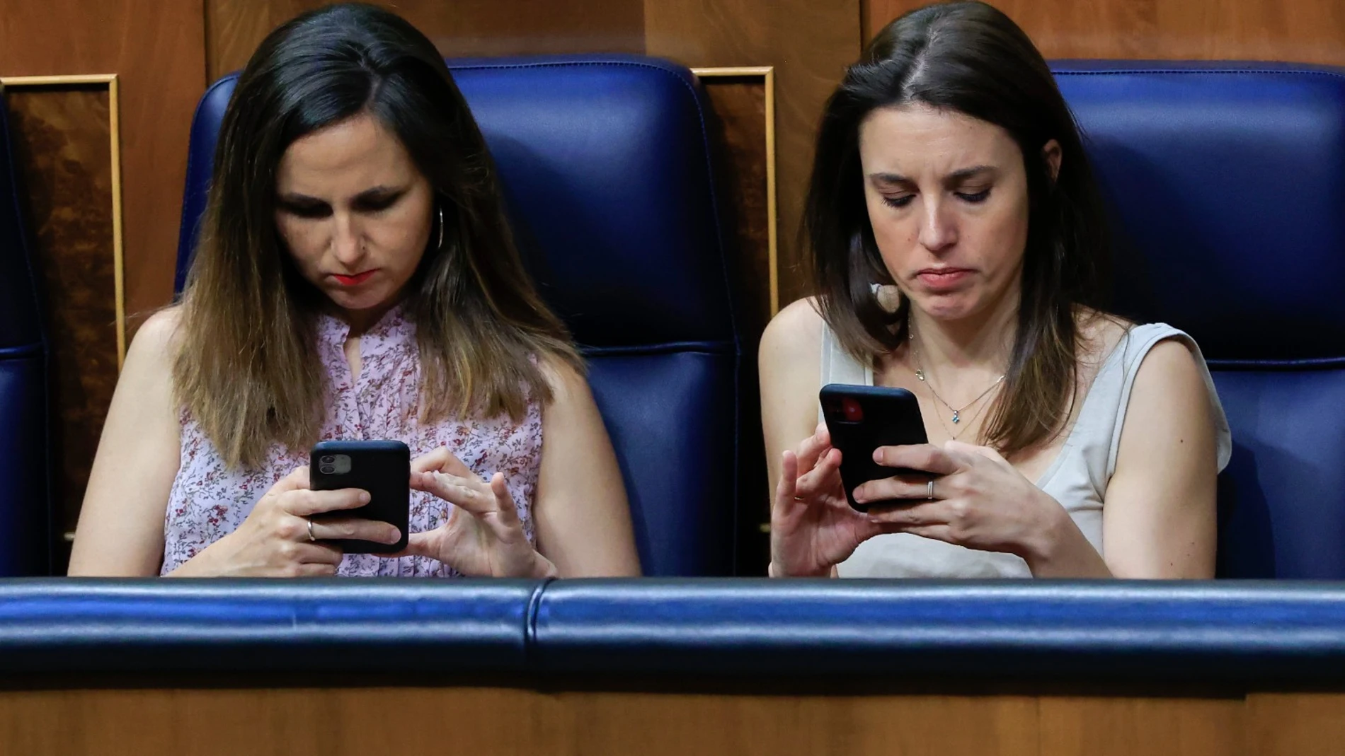 Irene Montero y Ione Belarra miran sus móviles en el Congreso