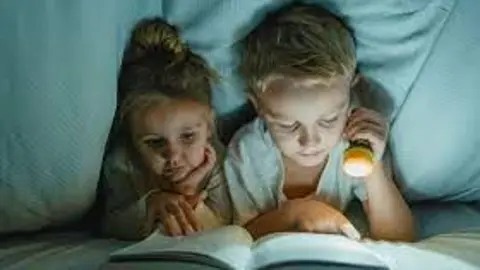 Lectura nocturna de dos niños