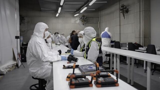 Miembros del Instituto de Medicina Legal y Forense y de la Policía Nacional, con trajes de protección, en el laboratorio instalado en el Valle
