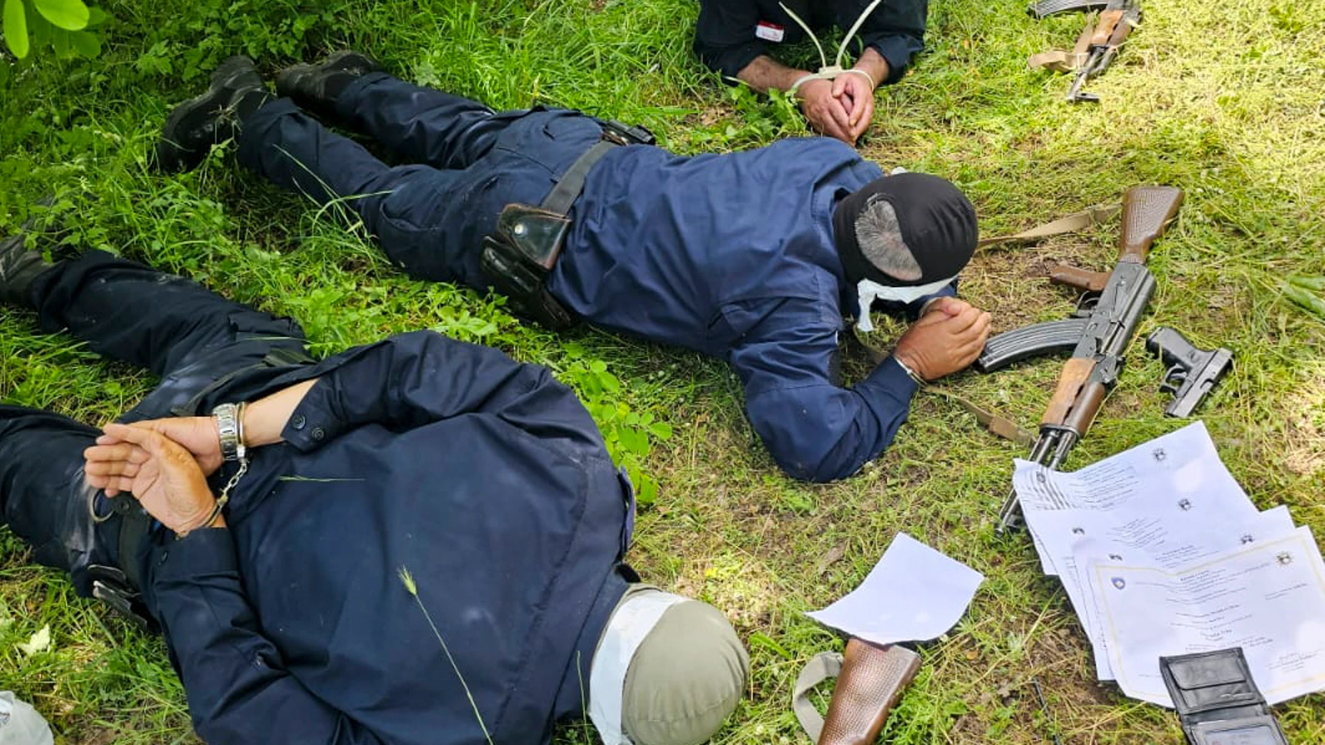 In this photo provided by the Serbian Ministry of Interior, a three Kosovo police officers captured by Serbian police officers lying face down on a field, on Wednesday, June 14, 2023. Serbian authorities said Wednesday they have captured three "fully armed" Kosovo police officers inside Serbia near their mutual border, while Kosovo police said they have likely been "kidnapped" on Kosovo territory as they patrolled the area. (Serbian Ministry of Interior via AP)