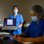 Leyre Herrero muestra la imagen de un embrión mientras la bióloga Rebeca Bravo trabaja junto a las incubadoras antiguas, una especie de cajas azules y negras, y modernas, blancas y verdes con una pantalla